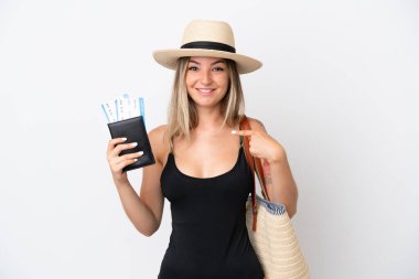 Elinde pasaport tutan mayo giymiş genç bir kadın beyaz arka planda, şaşırmış bir yüz ifadesiyle izole edilmiş.