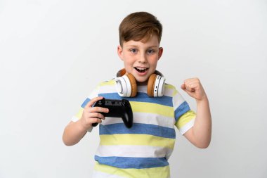 Küçük kızıl saçlı çocuk beyaz arka planda izole edilmiş bir oyun sahası tutuyor ve galibiyeti kutluyor.