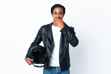 Beyaz arka planda izole edilmiş motosiklet kaskı tutan Afrikalı Amerikalı bir adam mutlu ve ağzı eliyle kaplayan bir gülümseme.