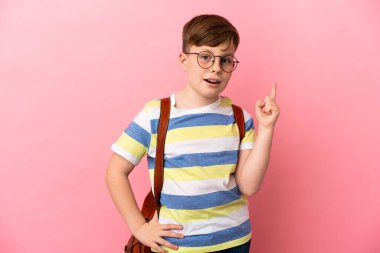 Küçük kızıl saçlı beyaz çocuk, pembe arka planda izole edilmiş.