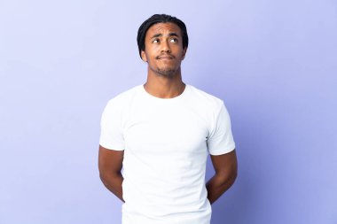 Örgülü genç Afrikalı Amerikalı adam mor arka planda izole edilmiş ve yukarı bakıyor.