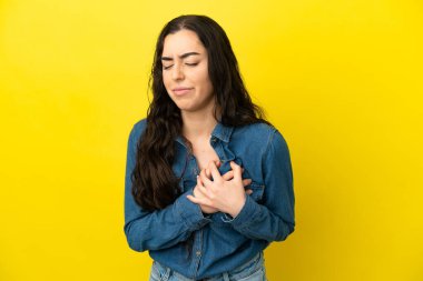 Sarı arka planda izole edilmiş beyaz bir kadın. Kalbinde ağrı var.