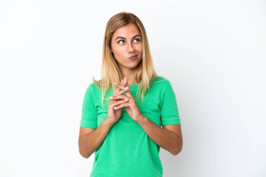 Sarışın Uruguaylı kız beyaz arka planda bir şeyler planlıyor.