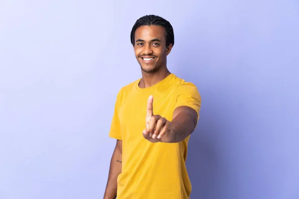 年轻的非裔美国人 头戴辫子 身披紫色背景 露出并举起一只手指头 — 图库照片