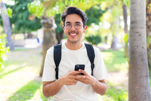 Young student man at outdoors using mobile phone