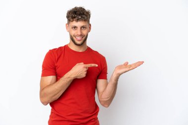 Beyaz arka planda izole edilmiş beyaz tenli yakışıklı bir adam, bir ilan vermek için avucunda hayali bir fotokopi makinesi tutuyor.