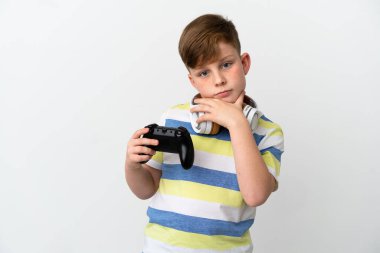 Küçük kızıl saçlı çocuk beyaz arka planda izole edilmiş bir oyun sahası tutuyor.