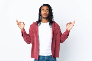 Beyaz arka planda Zen pozu almış örgülü Afro-Amerikan bir adam.