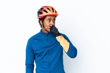 Arka planda örgü ören genç bisikletçi yan tarafa bakarken sürpriz jest yapıyor.