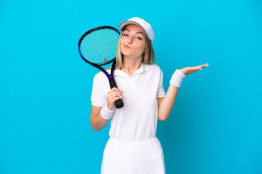 Genç tenisçi Romen kadın, mavi arka planda yalnızken ellerini kaldırırken şüpheye düştü