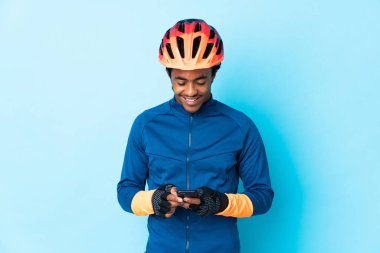 Örgü ören genç bir bisikletçi, izole edilmiş arkaplanda cep telefonuyla mesaj gönderiyor.