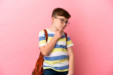 Küçük kızıl saçlı beyaz çocuk pembe arka planda izole edilmiş ve yukarı bakıyor.