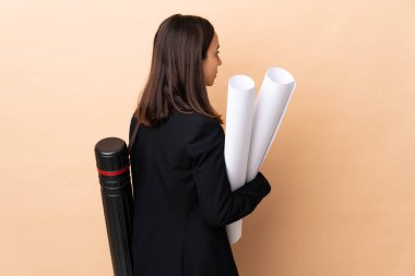 Genç mimar kadın arka planda izole edilmiş arka planla ilgili planlar tutuyor ve geriye bakıyor.