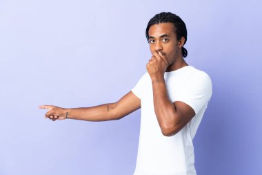 Örgülü genç Afrikalı Amerikalı adam, mor arka planda, sürpriz bir ifadeyle izole edilmiş.