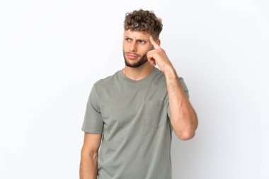 Beyaz arka planda soyutlanmış beyaz tenli yakışıklı bir adam deliliğin hareketini yapıyor. Parmağını kafaya koyuyor.