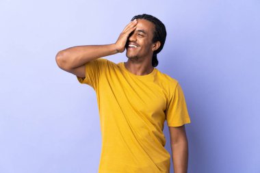 Örgülü genç Afrikalı Amerikalı adam mor arka planda izole edilmiş, çok gülümsüyor.