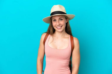 Yaz tatilinde beyaz bir kadın mavi arka planda yalnız gülüyor.