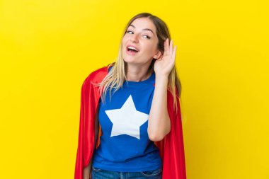 Süper kahraman Romen kadın sarı arka planda izole edilmiş bir şekilde elini kulağına koyarak bir şeyler dinliyor.