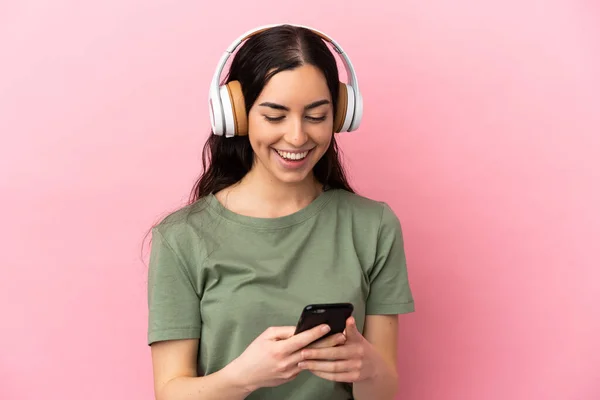 Jeune Femme Caucasienne Isolée Sur Fond Rose Écoutant Musique Regardant — Photo