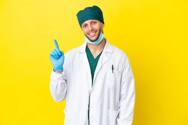 Χειρούργος Ξανθός Άνδρας Πράσινη Στολή Απομονώνονται Κίτρινο Φόντο Δείχνει Και — Φωτογραφία Αρχείου