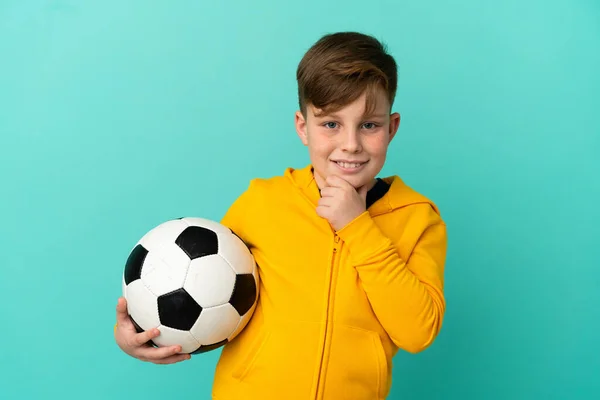 Roodharige Kind Spelen Voetbal Geïsoleerd Blauwe Achtergrond Kijken Naar Zijkant — Stockfoto
