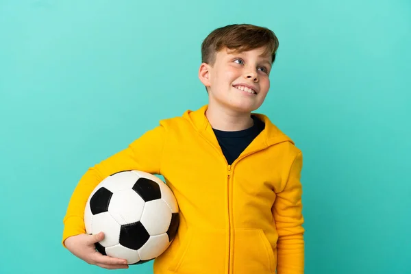 Roodharige Kind Spelen Voetbal Geïsoleerd Blauwe Achtergrond Denken Een Idee — Stockfoto