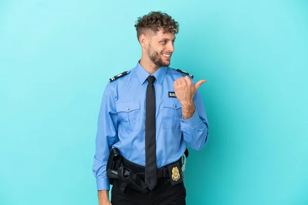 Young police blonde man isolated white on blue background pointing to the side to present a product