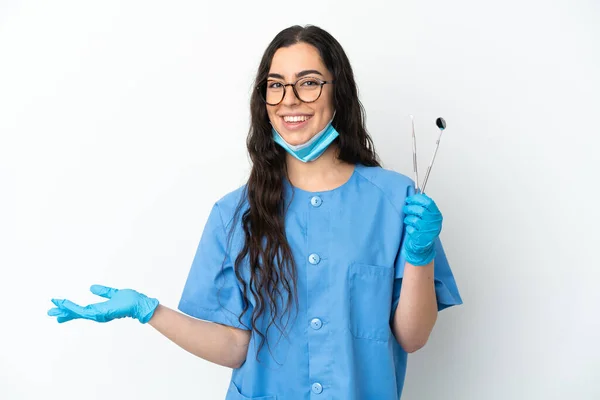 Młoda Kobieta Dentysta Trzyma Narzędzia Izolowane Białym Tle Wyciągając Ręce — Zdjęcie stockowe