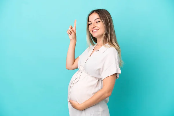 Junge Rumänin Isoliert Auf Blauem Hintergrund Schwanger Und Zeigt Nach — Stockfoto