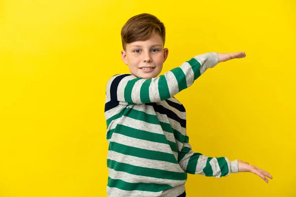 小红头发男孩被隔离在黄色的背景上 他拿着复制空间插入一个广告 — 图库照片