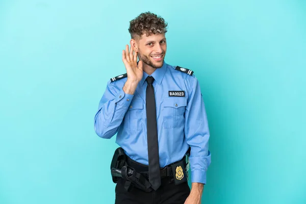 Joven Policía Rubia Hombre Aislado Blanco Sobre Fondo Azul Escuchando —  Fotos de Stock