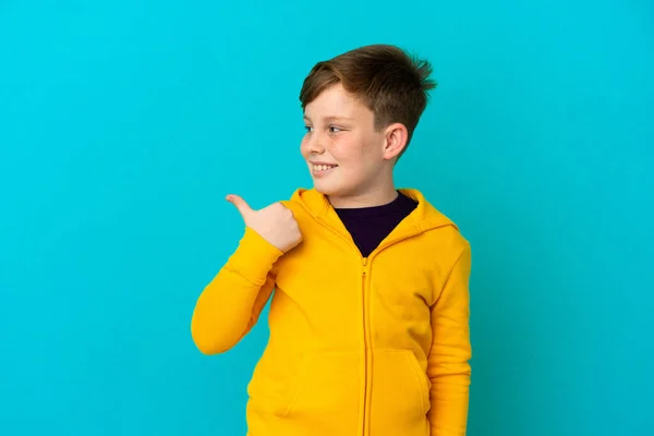 Liten Rödhårig Pojke Isolerad Blå Bakgrund Pekar Sidan För Att — Stockfoto