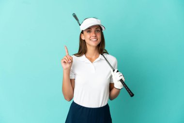 İzole edilmiş mavi arka planda golf oynayan ve en iyinin işareti olarak parmağını kaldıran kadın.