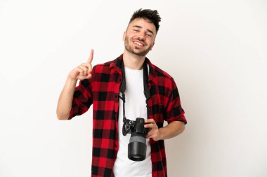 Beyaz arka planda izole edilmiş genç bir fotoğrafçı en iyinin göstergesi olarak parmağını kaldırıyor.