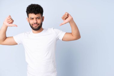 Genç Faslı adam mavi arka planda soyutlanmış gururlu ve kendini beğenmiş.