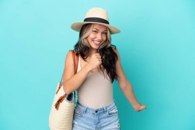 Pamel ve plaj çantalı genç Rus kız mavi arka planda zaferi kutluyor.