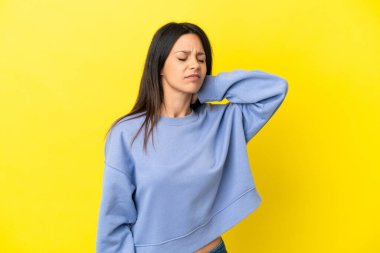 Sarı arka planda boynu ağrıyan genç beyaz kadın.