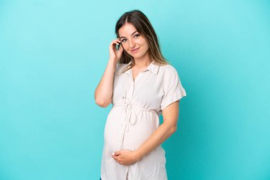 Genç Romen kadın mavi arka planda izole edilmiş hamile ve mutlu