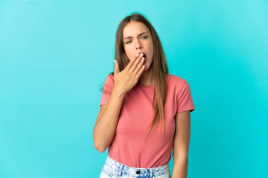 Izole mavi arka plan esneme üzerinde genç kadın esneme ve el ile geniş açık ağız kapsayan