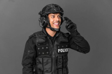 Özel Tim 'in beyaz adamı gri arka planda izole edilmiş ve cep telefonuyla sohbet ediyor.