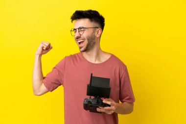 Sarı arka planda uzaktan kumandayı elinde tutan adam zaferi kutluyor.