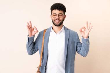 Genç Faslı iş adamı, zenli bej arka planda izole edilmiş.