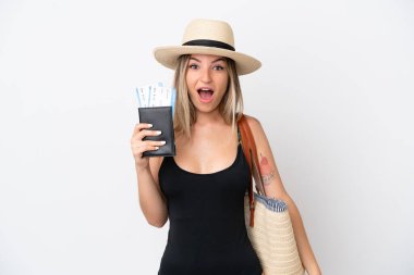 Mayo giymiş, elinde pasaport olan genç bir kadın beyaz arka planda, şaşırmış ve şok olmuş bir yüz ifadesiyle izole edilmiş.