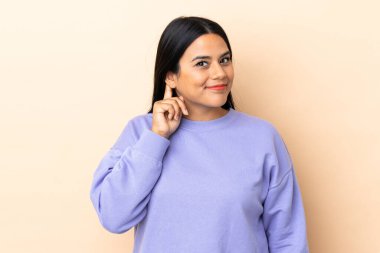 Genç Latin kadın arka planda yalnız gülüyor.