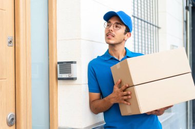 Dışarıda kutuları tutan genç teslimatçı.