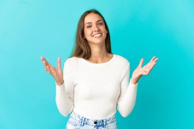 Soyutlanmış mavi arka planda genç bir kadın. Çok gülümsüyor.