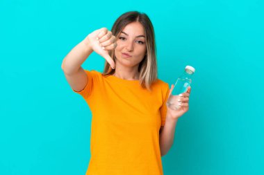 Mavi arka planda izole edilmiş bir şişe suyu olan genç Romen kadın, olumsuz bir ifadeyle baş parmağını aşağı gösteriyor