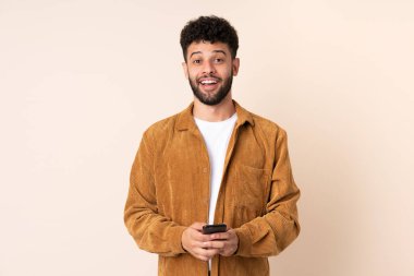 Bej arka planda izole genç Faslı adam şaşırdı ve bir mesaj gönderiyor.
