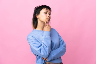 Genç Uruguaylı kadın soyutlanmış pembe arka planı araştırırken kuşkuları var.