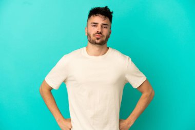 Kafkasyalı genç adam mavi arka planda izole edilmiş kızgın.